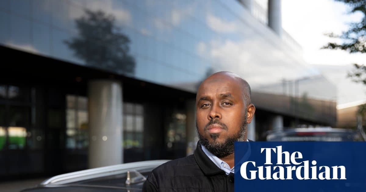 Un chauffeur de VTC debout à côté de sa voiture, photographié pour le reportage du Guardian sur l’action collective.