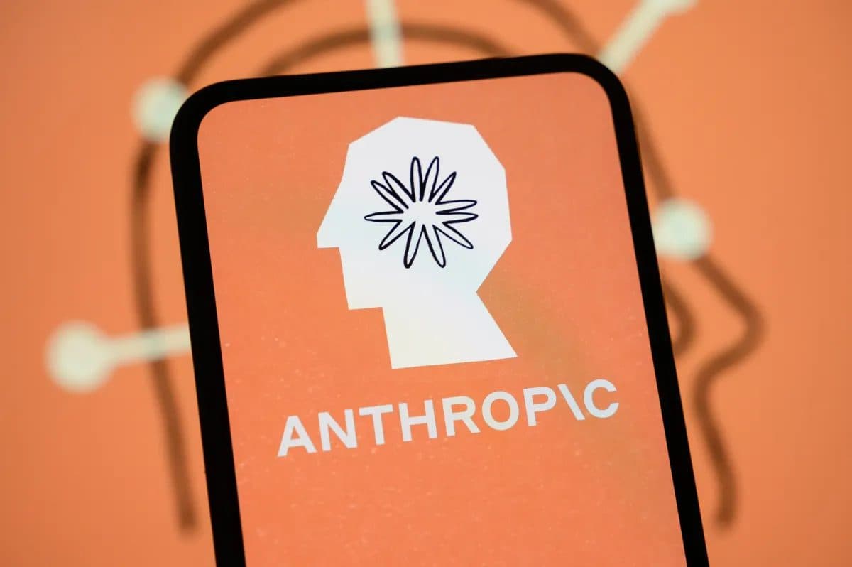 A smartphone displaying the Anthropic logo in white on an orange background, against an orange backdrop with abstract line shapes
