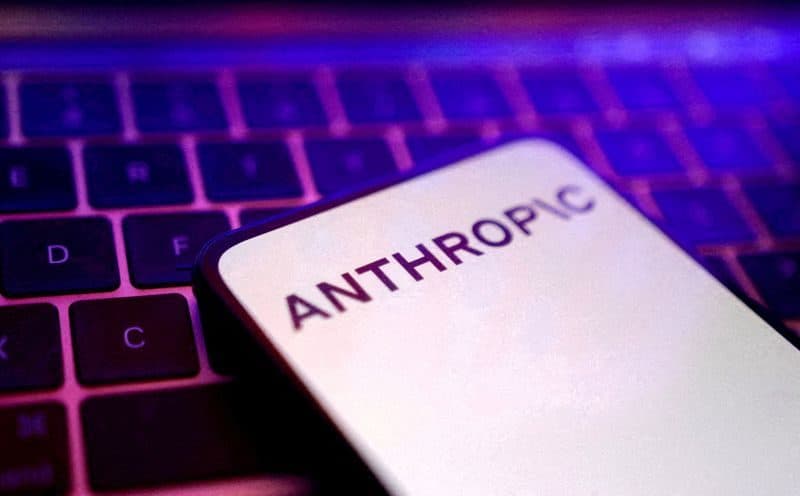 شاشة هاتف تعرض شعار Anthropic مضاءً باللون البنفسجي أمام لوحة مفاتيح.