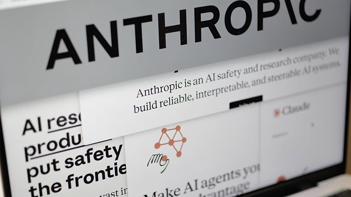 Primer plano de una página impresa con el nombre de Anthropic y una línea que la describe como una empresa de seguridad e investigación en IA, con una pantalla al fondo.