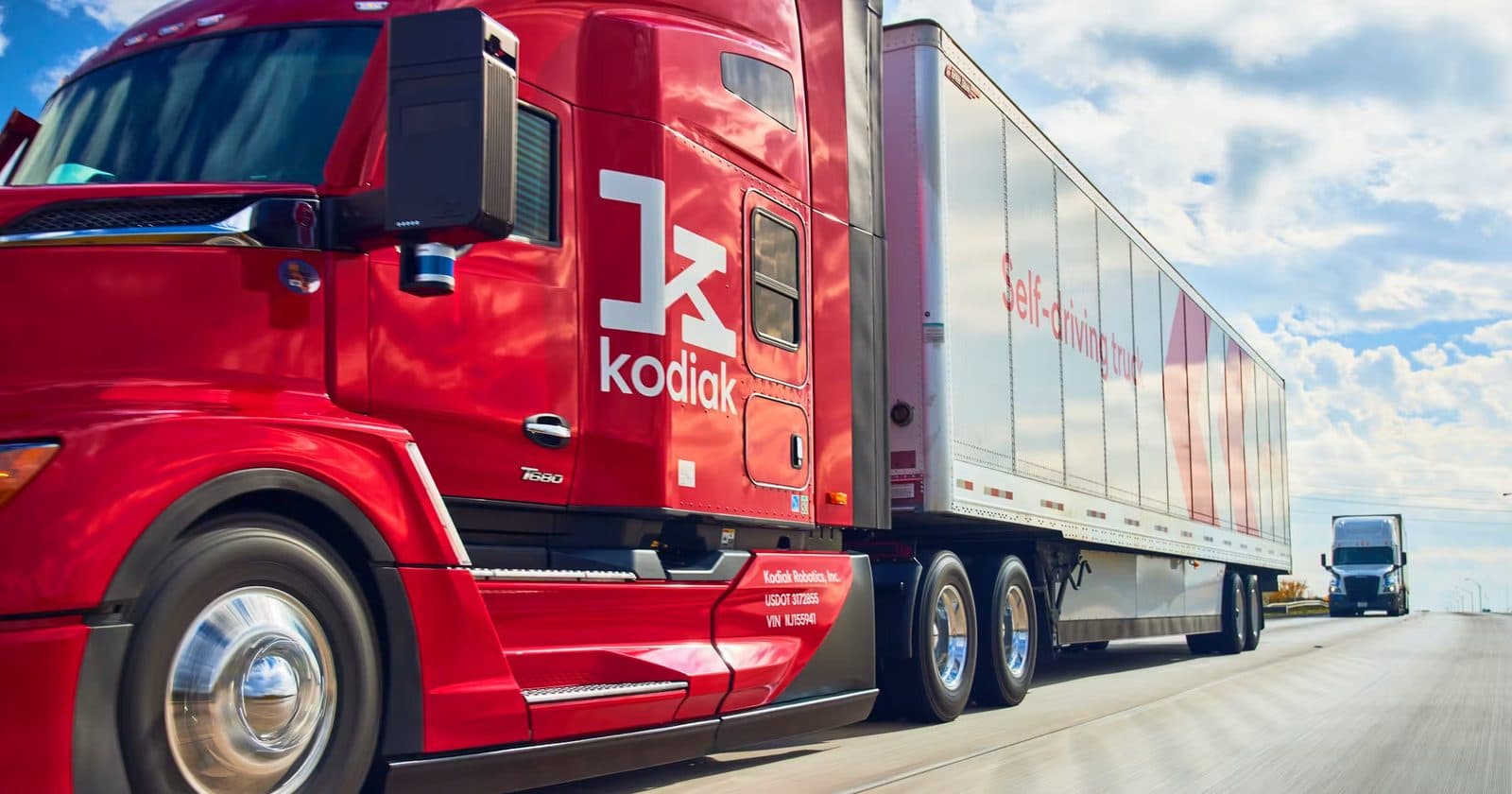 A red Kodiak-branded autonomous semi-truck on a highway.