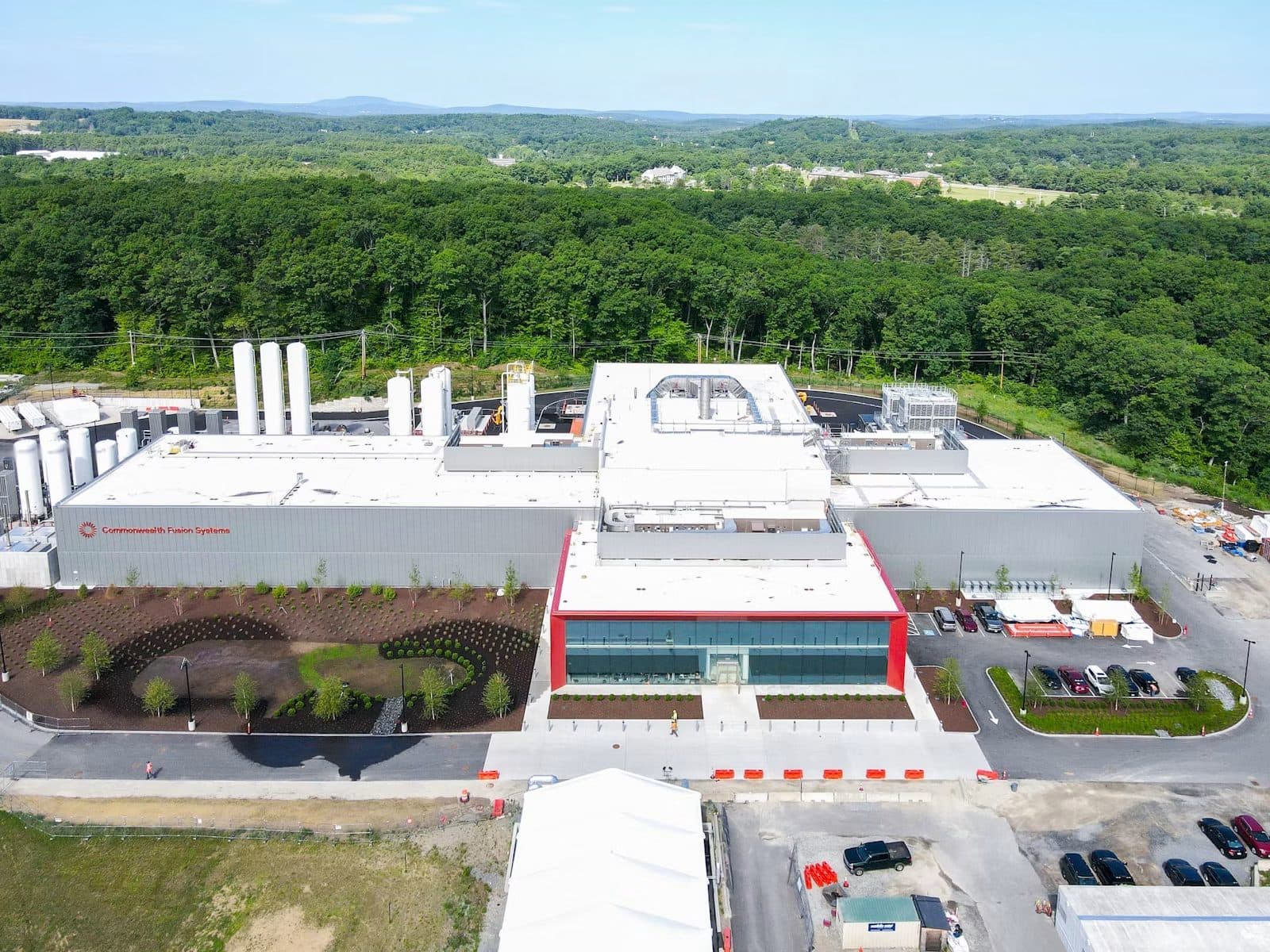 An aerial view of a Commonwealth Fusion Systems facility and its car park, surrounded by woodland.