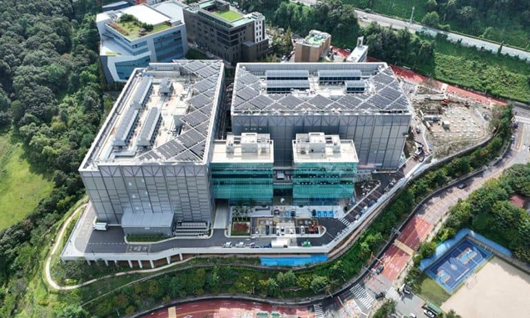 Veduta aerea del Pacific Sunny Data Center costruito da Hyundai E&C a Yongin, nella provincia di Gyeonggi, Corea del Sud, un complesso grigio e basso circondato da colline boscose.