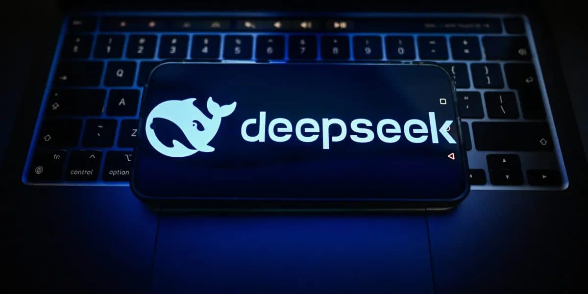 어두운 방에서 파란빛이 비치는 노트북 위 휴대전화 화면에 DeepSeek 고래 로고와 워드마크가 보인다