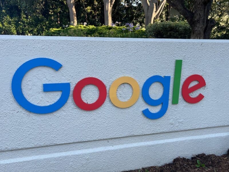 Google 캠퍼스 바깥 흰 벽에 설치된 다색 Google 로고와 뒤편의 나무들.