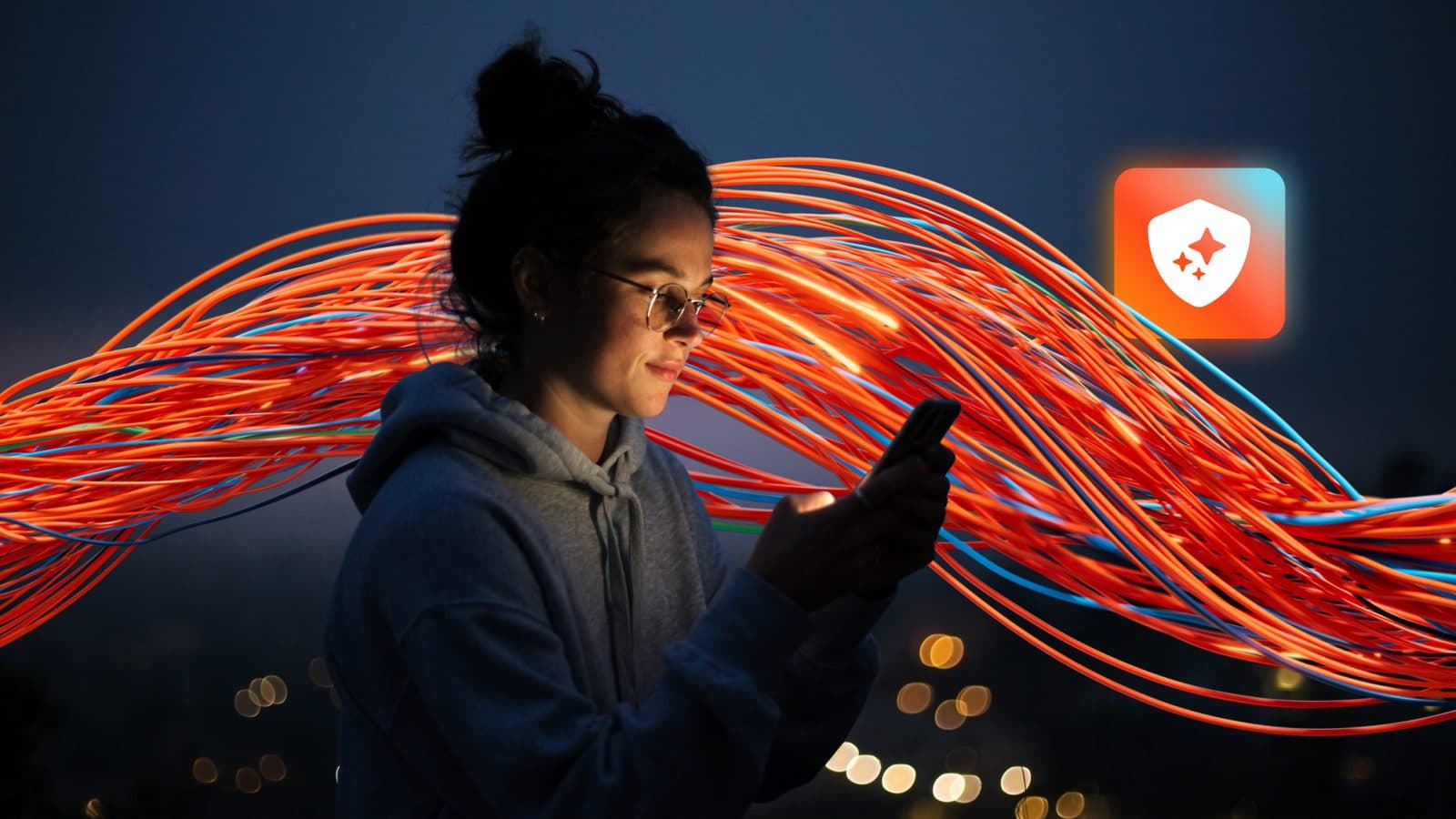 Immagine stock di una donna che guarda un telefono mentre flussi di luce arancioni e rossi curveggiano accanto a lei, con un’icona a scudo; immagine marketing di Genesys, non una foto del prodotto.