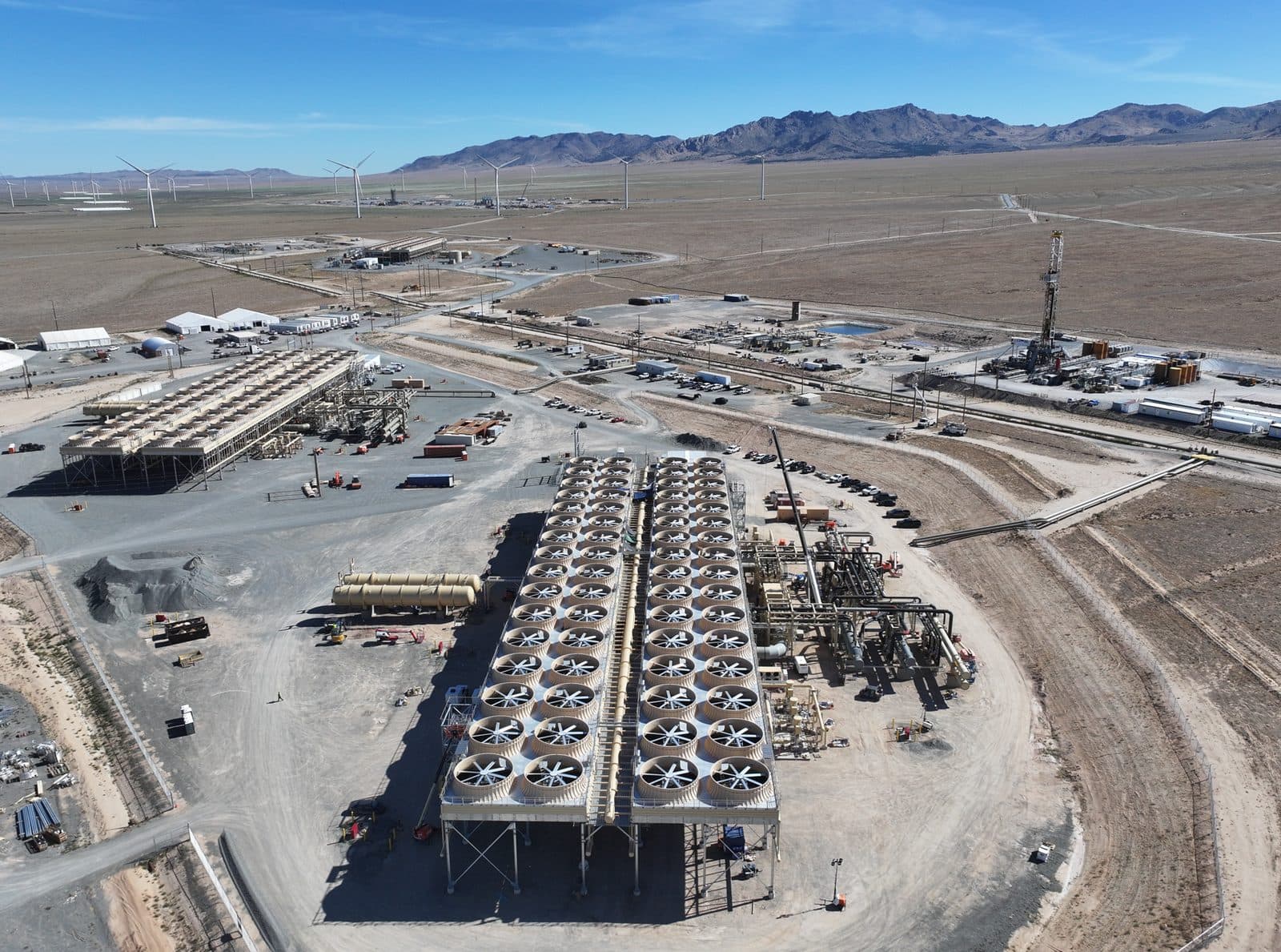 An aerial view of Fervo Energy's Cape Station site in the Utah desert, showing rows of well pads and plant equipment against bare hills.
