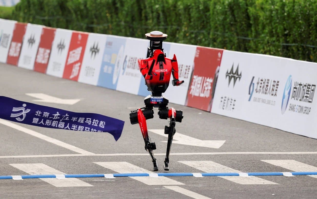 Um robô humanoide vermelho correndo ereto em um percurso fechado de rua, com faixas de patrocinadores em chinês, em um evento de maratona para robôs.