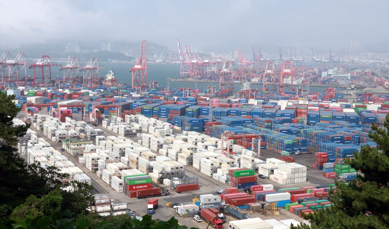 Stacked shipping containers and gantry cranes at a container port