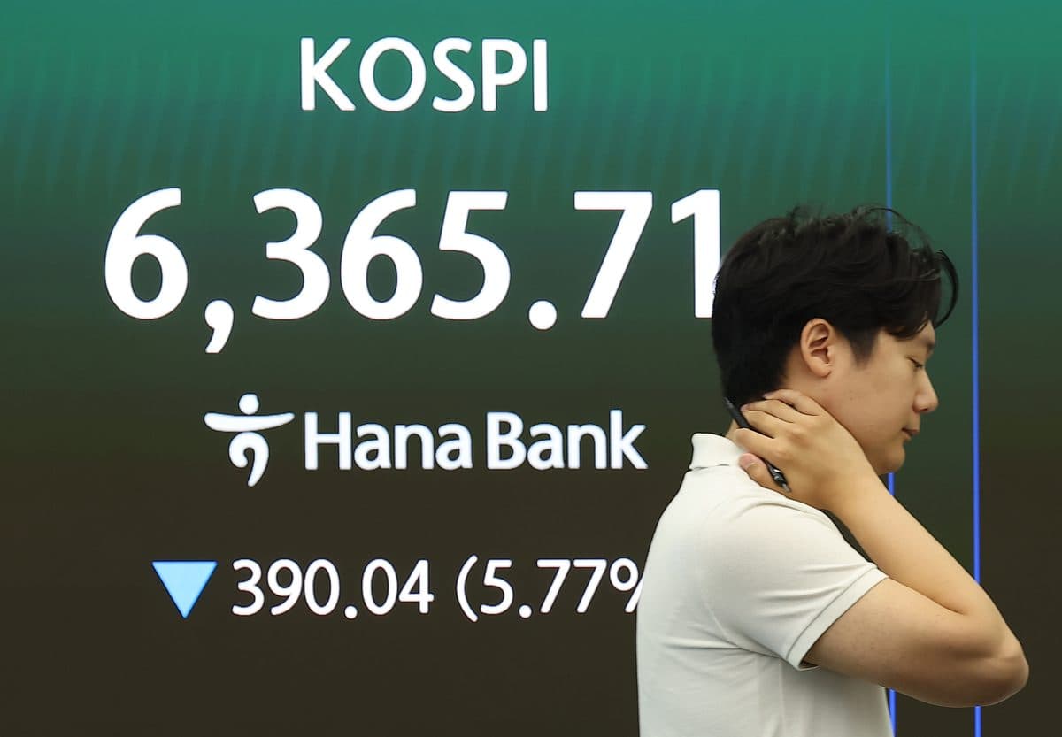 Un homme se massant la nuque devant un écran de salle de marché à Séoul ; l'affichage indique KOSPI 6,365.71, en baisse de 390.04 points, à un niveau intrajournalier bien supérieur à la clôture du jour
