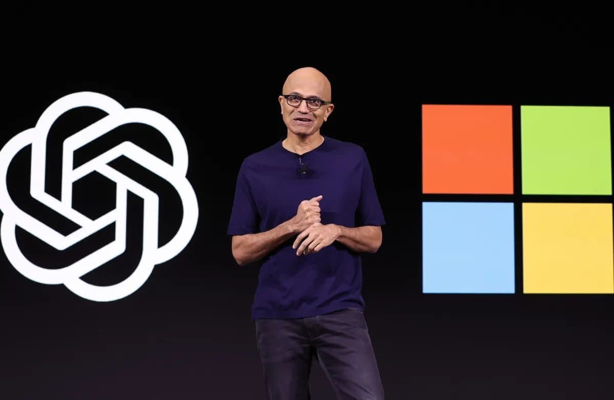 Satya Nadella sul palco tra i loghi di OpenAI e Microsoft.