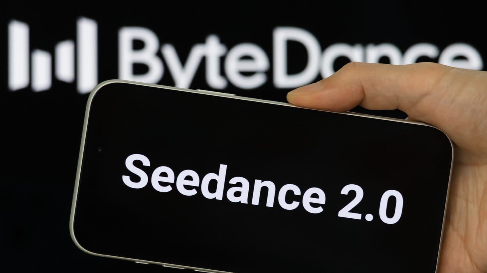 A hand holding a smartphone displaying the words 'Seedance 2.0', with the ByteDance logo on a wall behind it