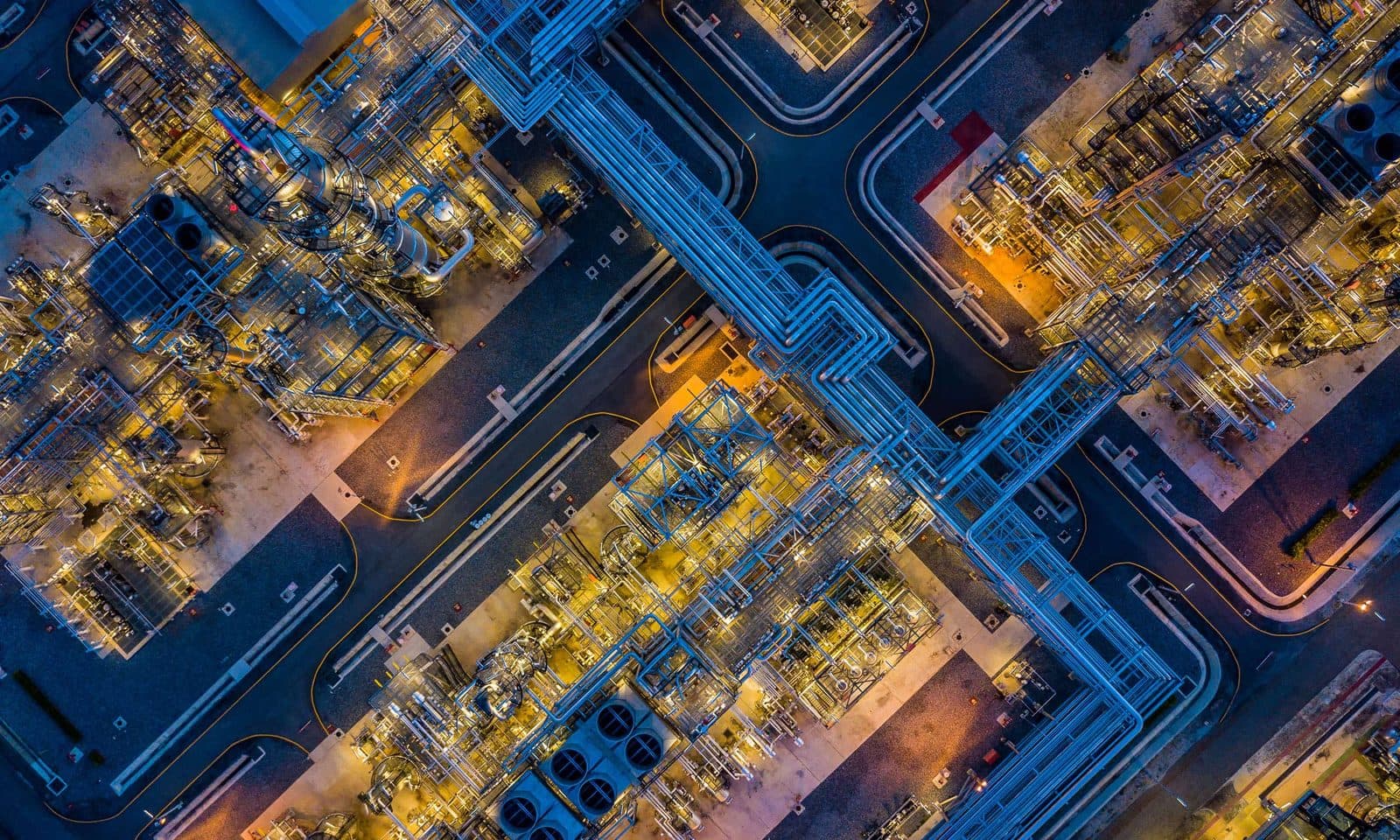 Uma vista noturna aérea de um complexo industrial denso, iluminado em azul e âmbar, usada pela IOP Publishing como ilustração na página de notícias.
