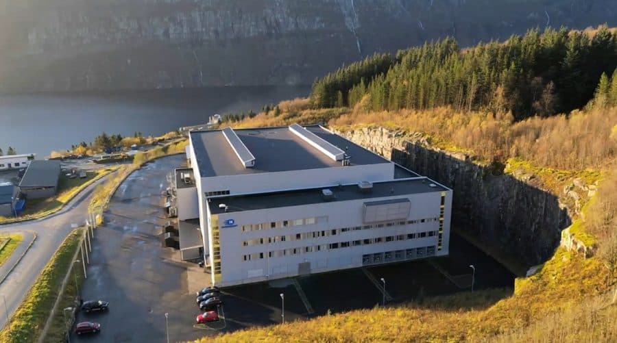 An aerial view of an Nscale data-centre building set into a wooded hillside.