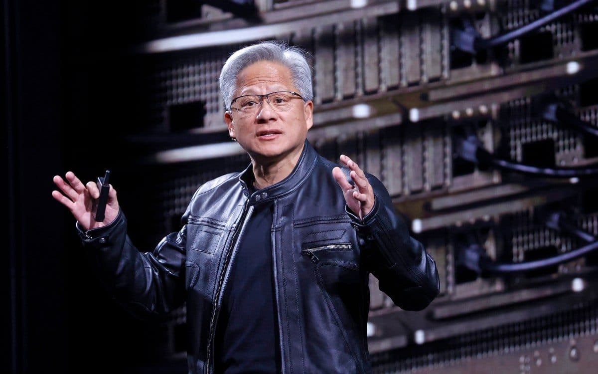 Il CEO di Nvidia Jensen Huang parla sul palco davanti a una parete di rack di server.