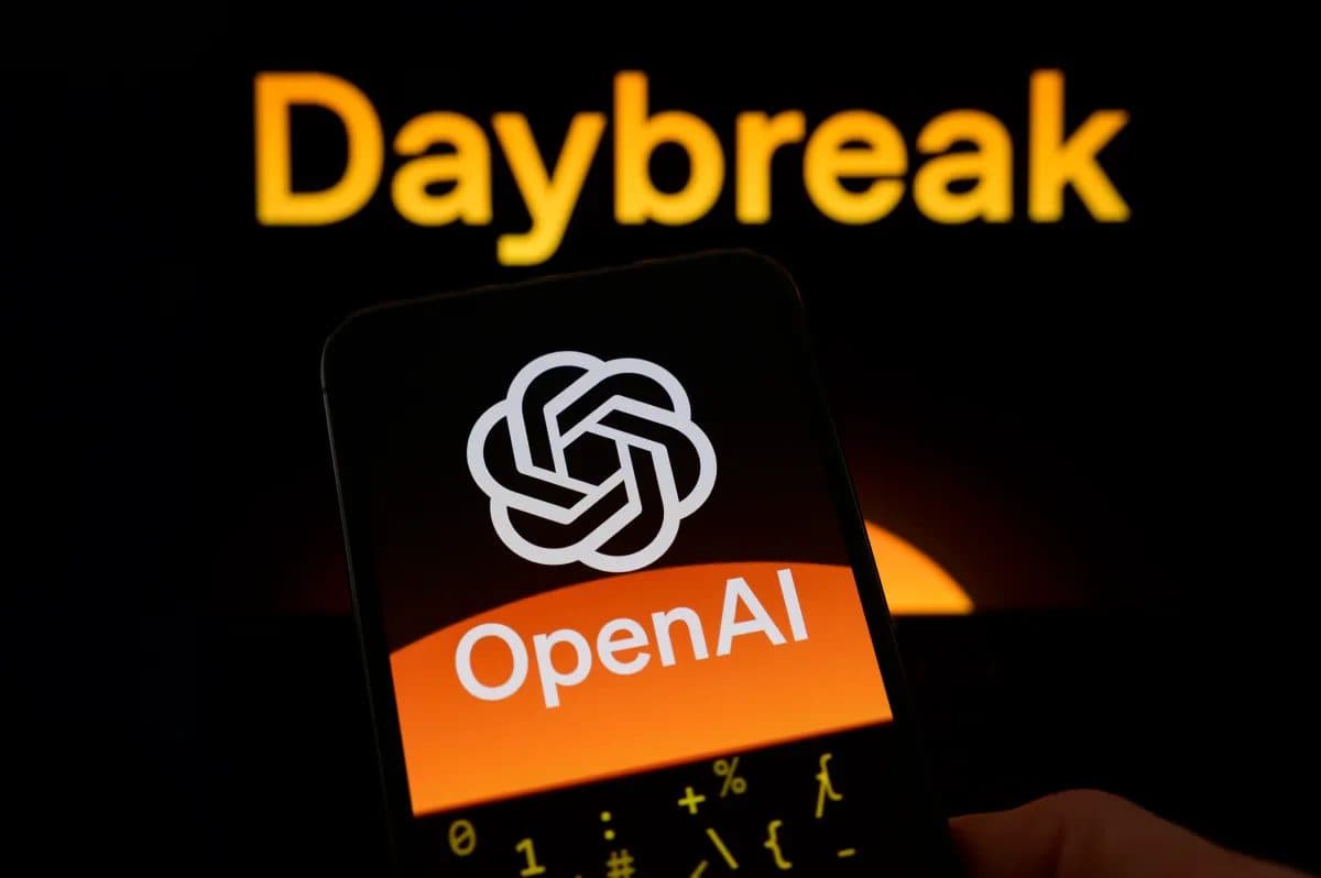 A smartphone displaying the OpenAI logo, held against a dark background beneath the illuminated word "Daybreak".