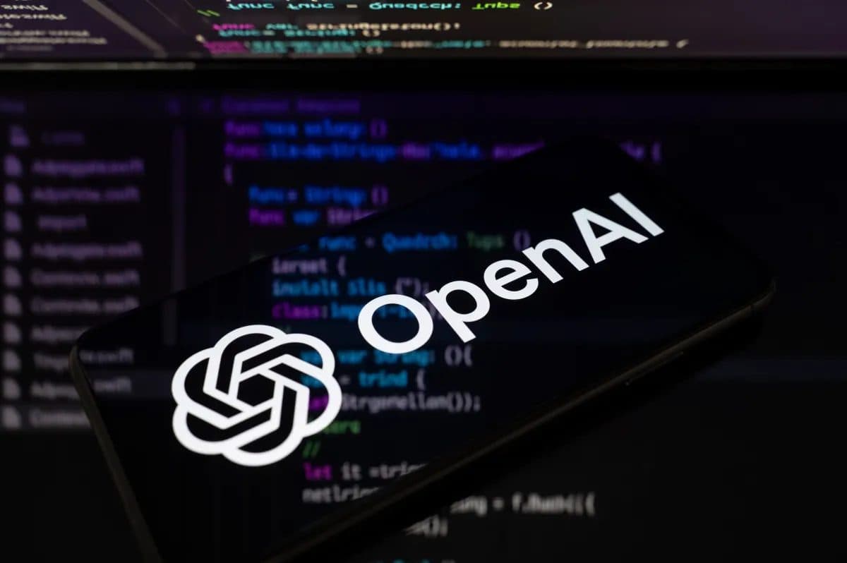 스마트폰 위에 놓인 OpenAI 로고가 소스 코드가 가득한 화면 위에 보입니다.