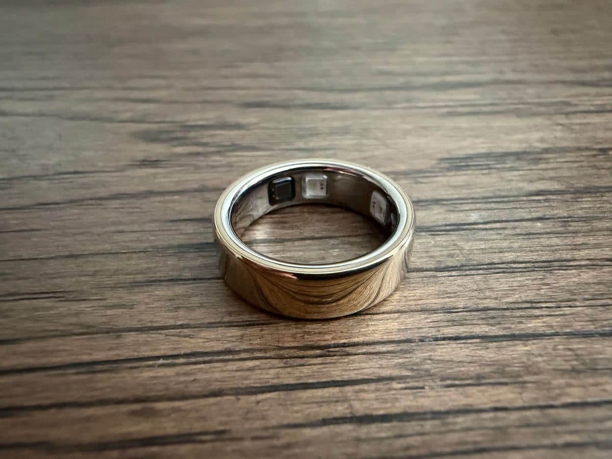 خاتم Oura ذهبي مطفي موضوع على سطح خشبي