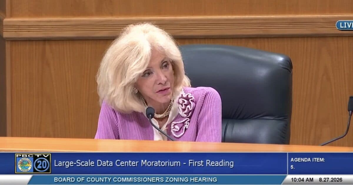 Imagens ao vivo de uma reunião com um comissário do Condado de Palm Beach falando na mesa, com a legenda na tela 'Large-Scale Data Center Moratorium - First Reading' e a data 8.27.2026