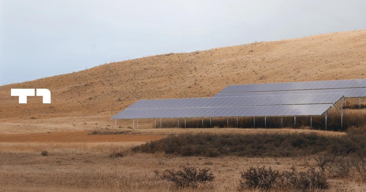A ground-mounted solar array on dry scrubland, with the T1 Energy logo overlaid
