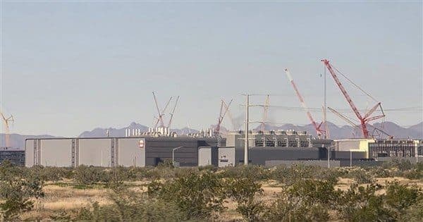 건설 중인 대형 반도체 제조 공장과 그 위로 서 있는 크레인, 건조한 지역의 저층 산업 건물들