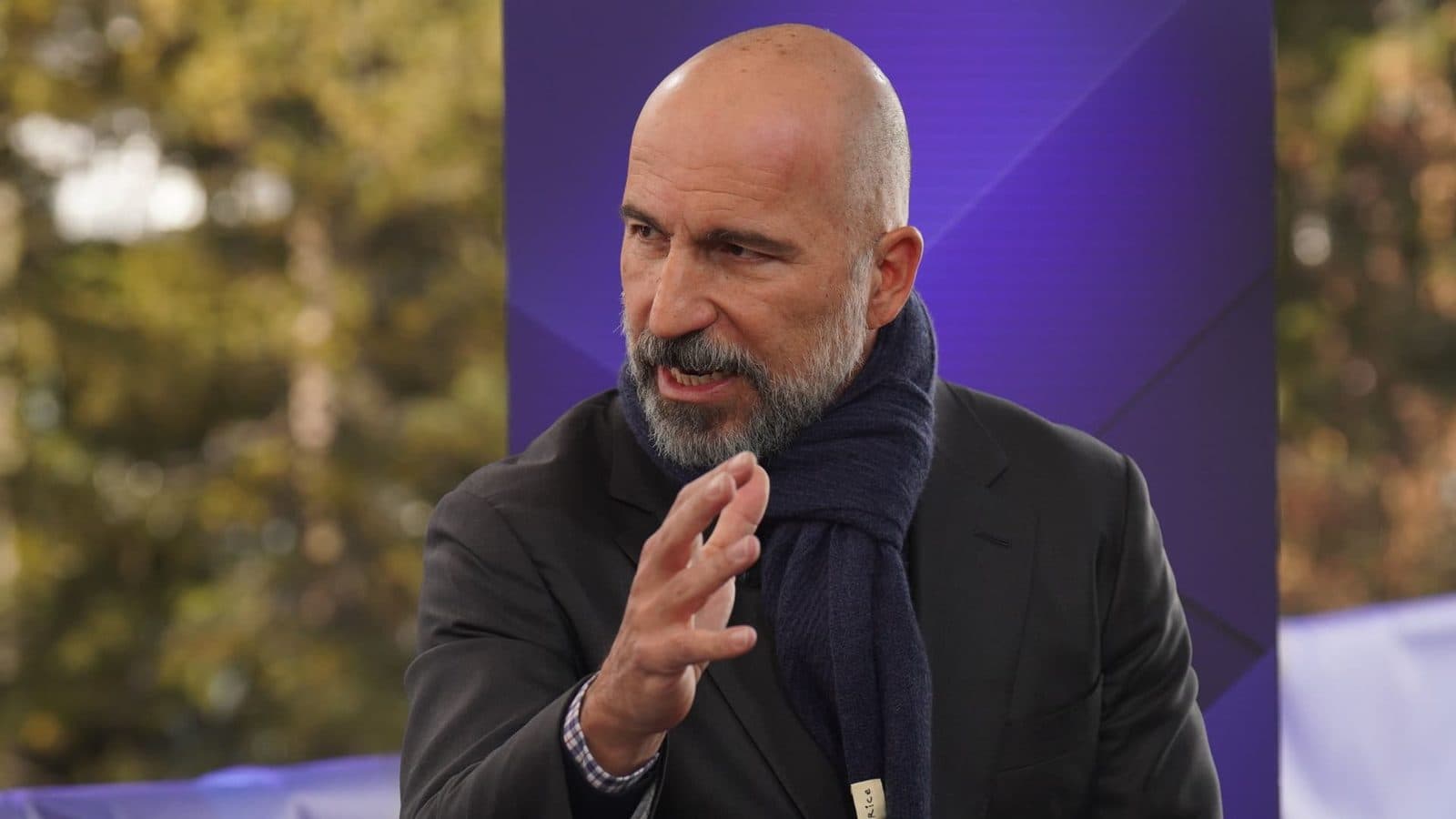 الرئيس التنفيذي لـ Uber Dara Khosrowshahi يتحدث على منصة أمام خلفية أرجوانية