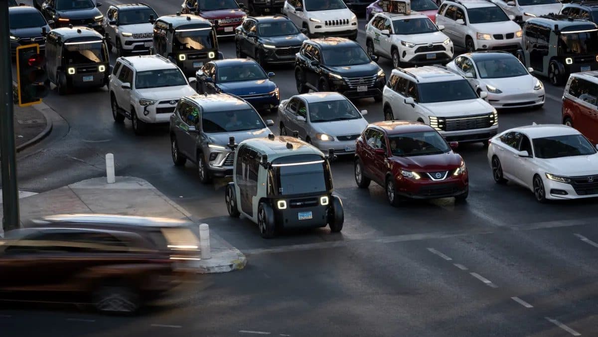 Un pod robotaxi Zoox nel traffico tra auto convenzionali su una strada a più corsie